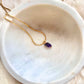 Amethyst necklace featuring a faceted purple gemstone pendant on a delicate gold chain
